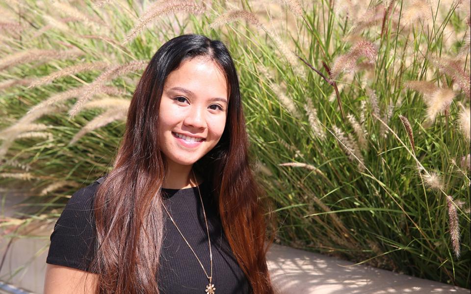 Alina Bonto poses in front of vegetation.