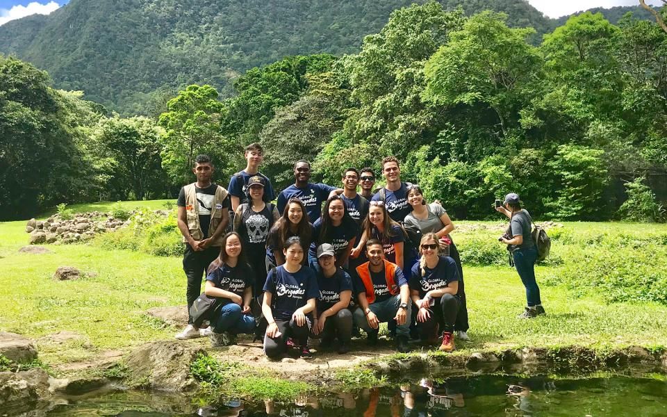 Students pose for a group photo in a lush area.