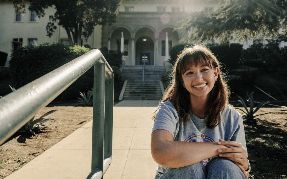 Student sitting on campus smiling